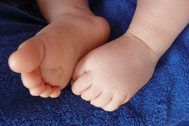 Geburtshilfe in der Flüchtlingsunterkunft Baby-Füße auf blauem Handtuch.
