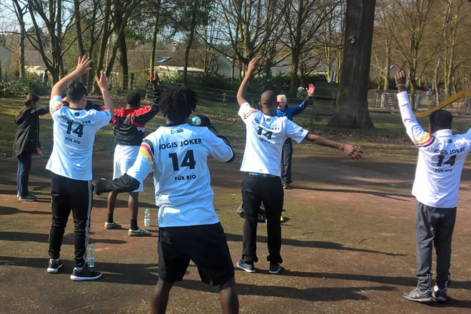 Teamwork beim Frühjahrslauf in Bad Godesberg Junger Männer in weißen Fußballtrikots machen Aufwärm-Übungen.