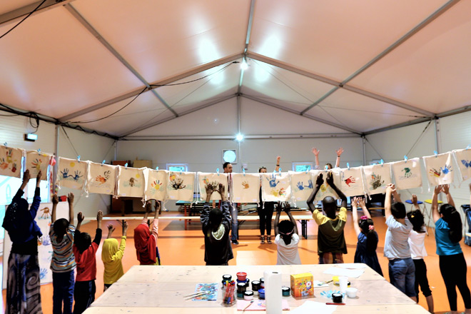 Kreatives Kinderfest in Unna-Massen Kinder strecken vor einer Wäscheleine voll bunter Jutebeutel ihre Arme in die Höhe.