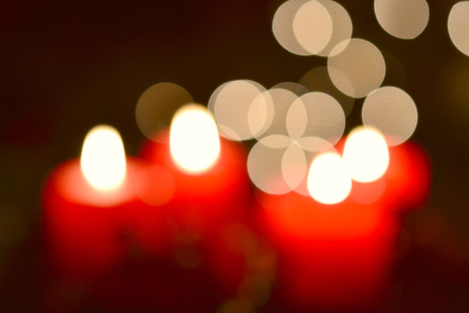Rote Kerzen und helle Lichtpunkte, unscharf.