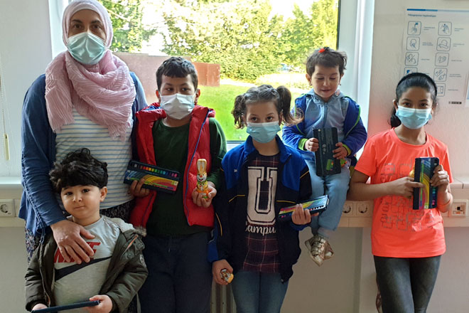 ZUE Bonn: Schoko-Osterhasen und bunte Stifte versüßen Oster-Freude Gruppenbild mit Kindern und einer Mutter.