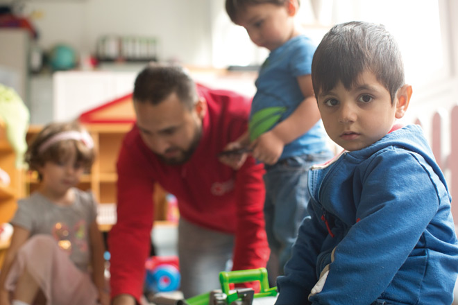 Ein Erzieher spielt mit drei Kindern in der Kinderspielstube