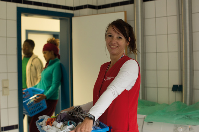 DRK-Mitarbeiterin trägt einen Wäschekorb