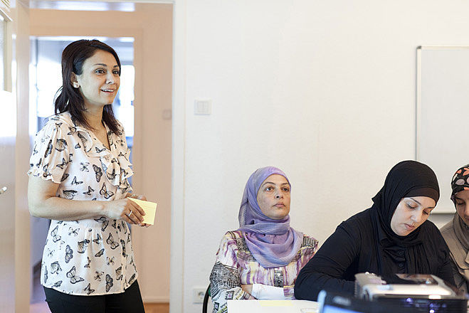 Im Klassenzimmer: Eine Lehrerin unterrichtet drei Schülerinnen, die Kopftücher tragen